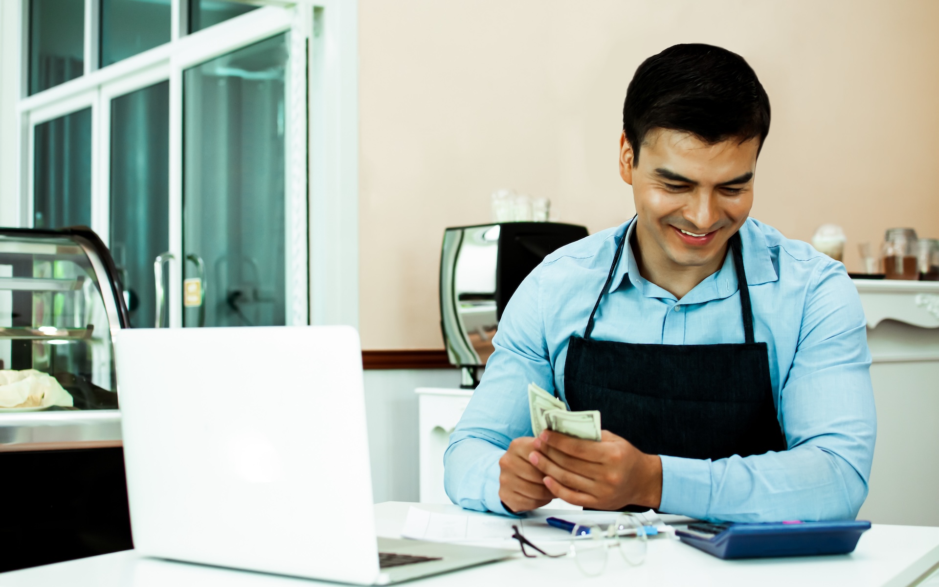 cafe owner smiles as he calculates the restaurant profit margin