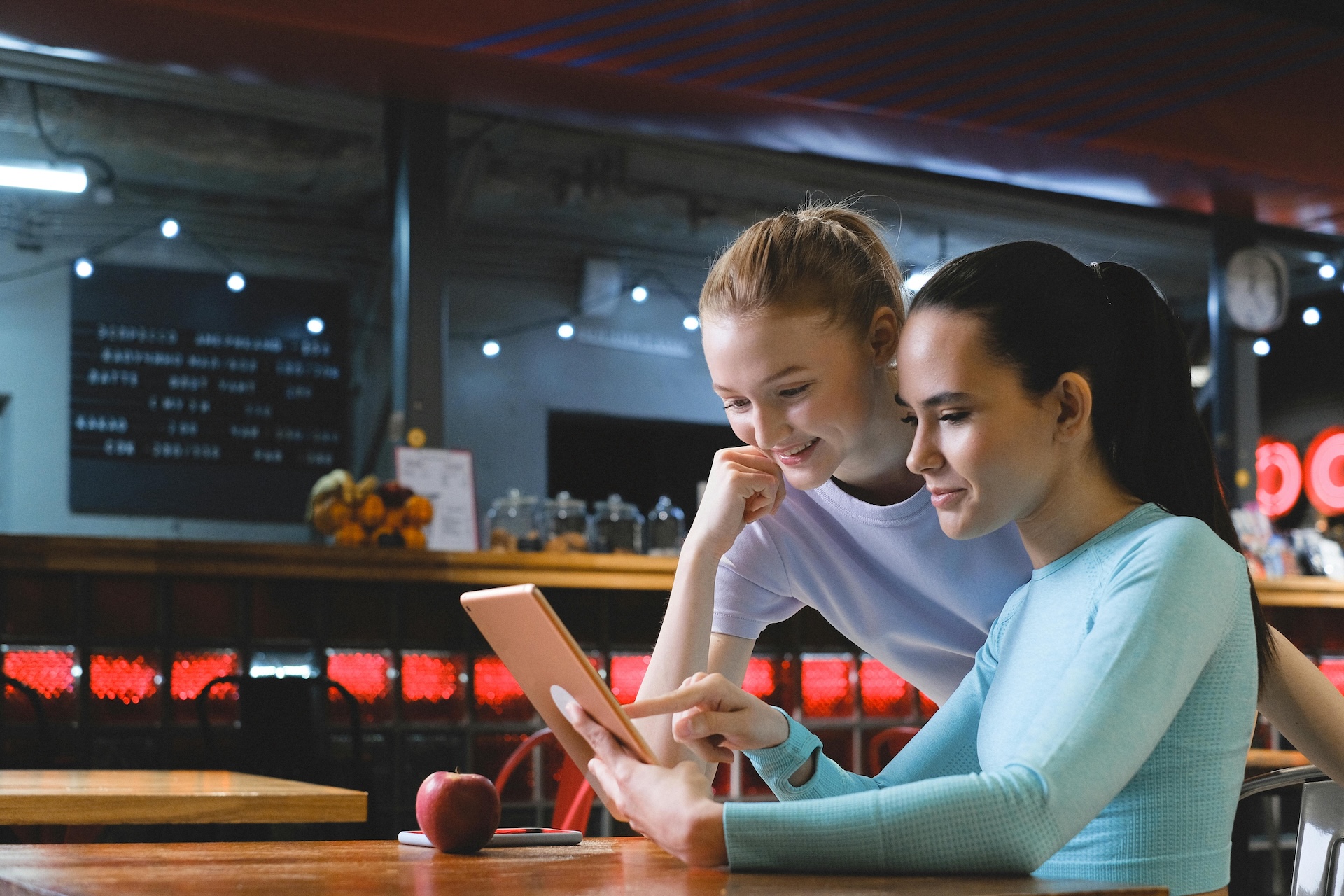 two woman at restaurant looking at tablet